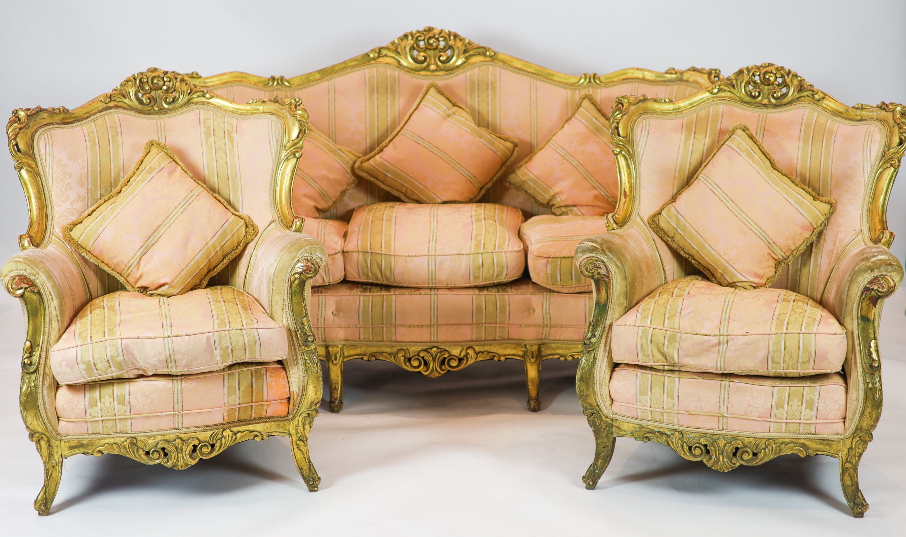 A Louis XV style carved gilt wood five piece suite, consisting of a three seater settee and four fauteuils, all with scroll carved backs and arms, on short cabriole legs